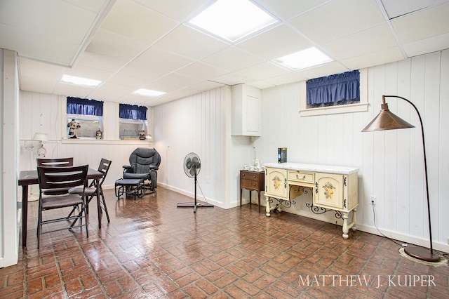 interior space with a drop ceiling and wooden walls