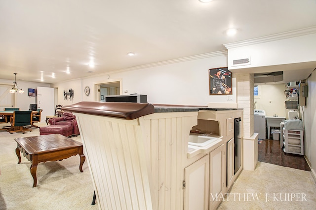 kitchen with light colored carpet, ornamental molding, and washer / clothes dryer