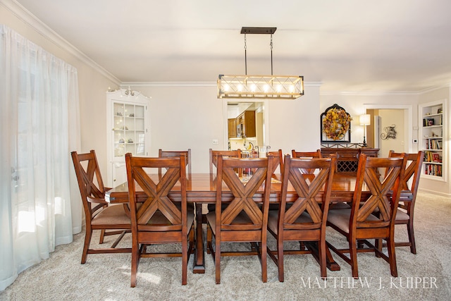 dining room with built in shelves, carpet floors, and crown molding