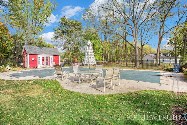 view of pool with a diving board, an outdoor structure, a yard, and a patio