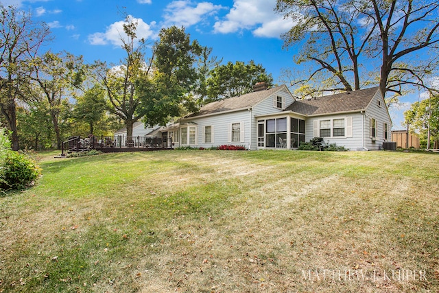 rear view of property with a sunroom, cooling unit, and a lawn