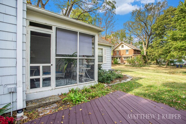 wooden deck with a sunroom and a lawn