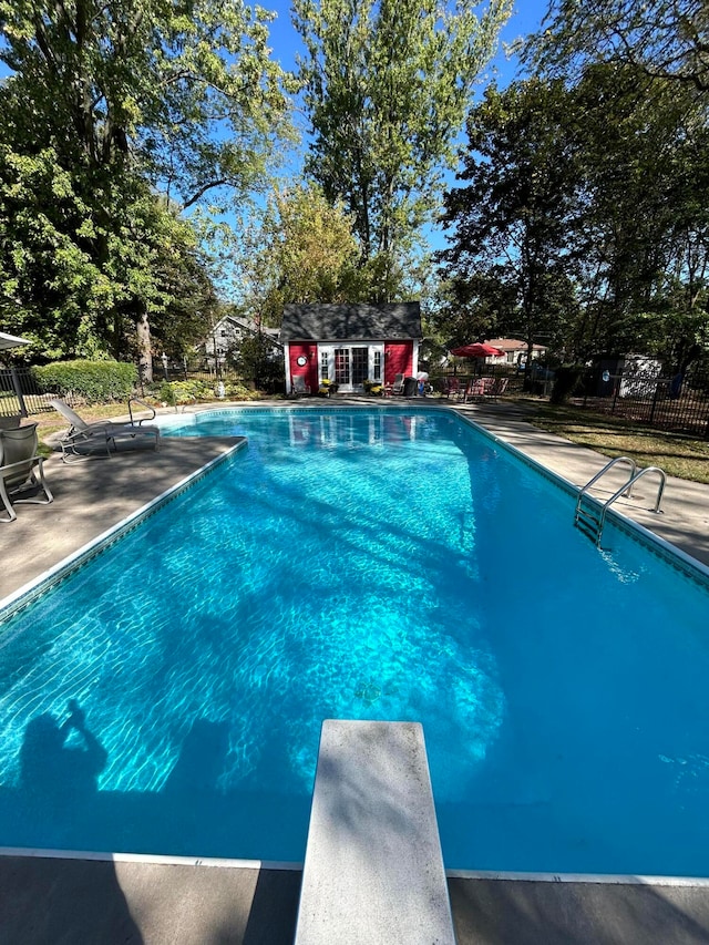 view of pool featuring a diving board, a patio area, and an outdoor structure