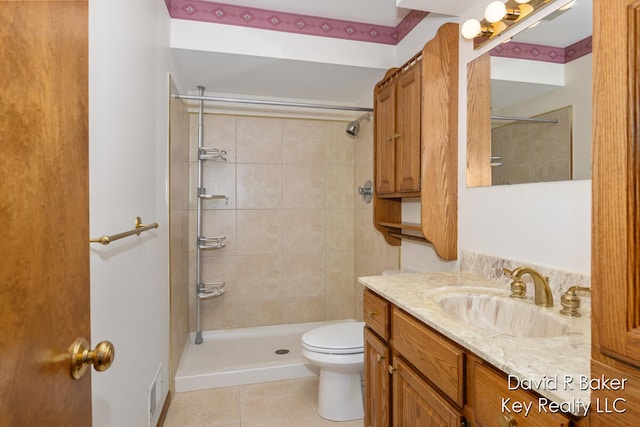 bathroom featuring tile patterned flooring, vanity, tiled shower, and toilet