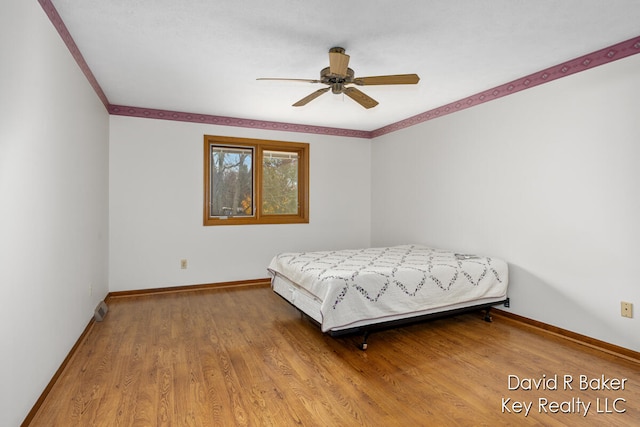 bedroom with hardwood / wood-style flooring, ceiling fan, and ornamental molding