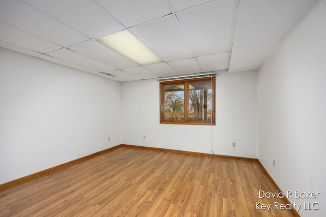 unfurnished room with hardwood / wood-style floors and a drop ceiling