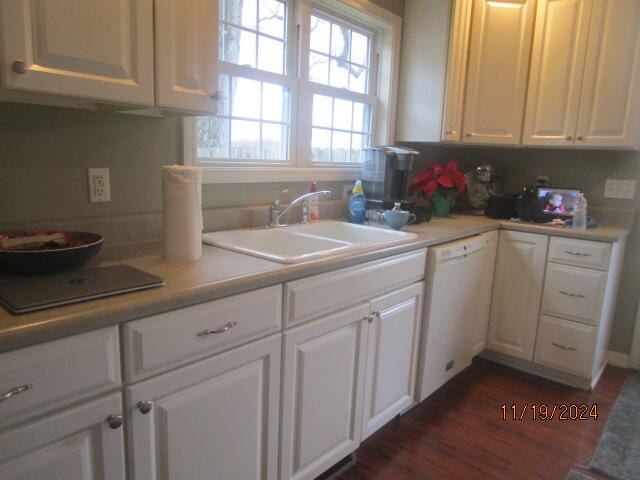 kitchen with dark hardwood / wood-style flooring, dishwasher, white cabinets, and sink