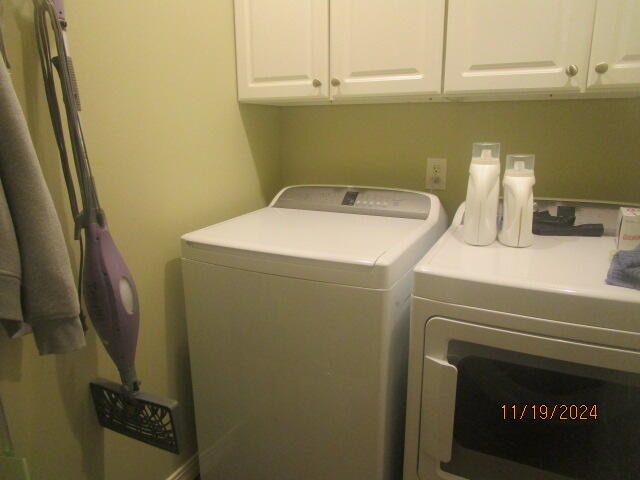 clothes washing area featuring cabinets and washing machine and clothes dryer