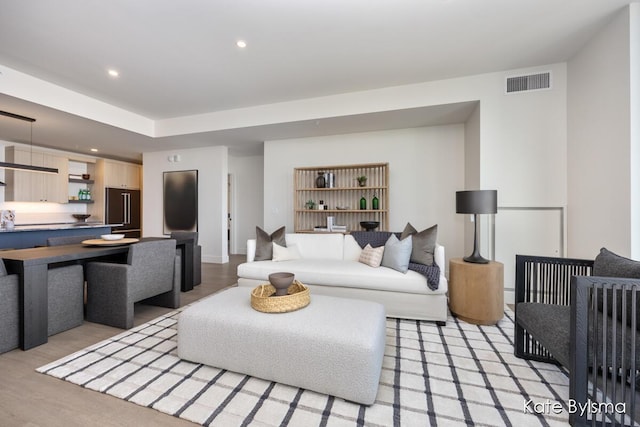 living room with recessed lighting, light wood-style flooring, and visible vents