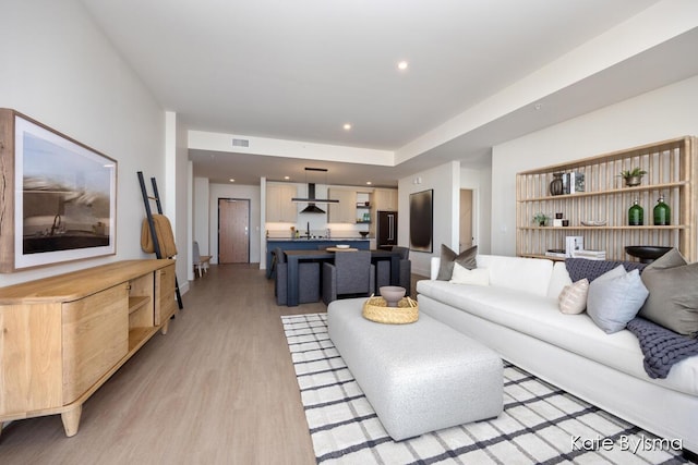 living room featuring light wood-style flooring, visible vents, and recessed lighting