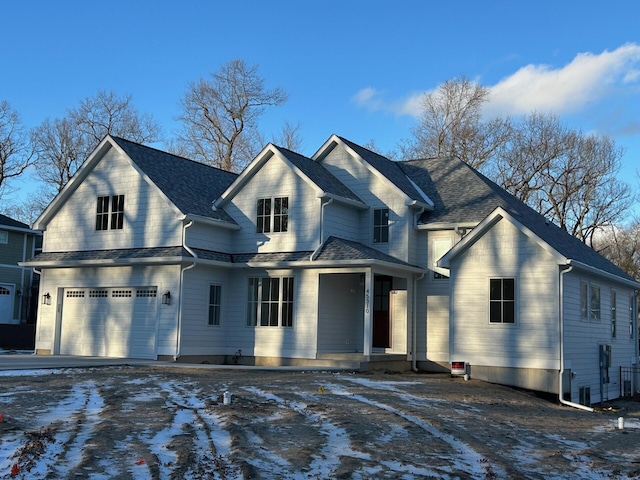 view of front of property featuring a garage, covered porch, a shingled roof, and driveway