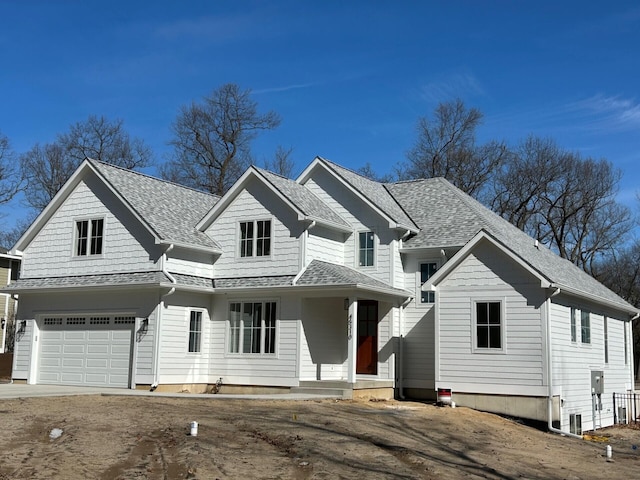 traditional home featuring roof with shingles and an attached garage