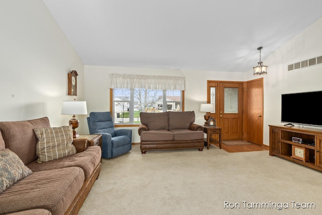 carpeted living room with a notable chandelier and lofted ceiling