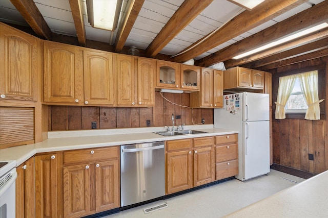 kitchen featuring wood walls, white refrigerator, sink, stainless steel dishwasher, and beamed ceiling