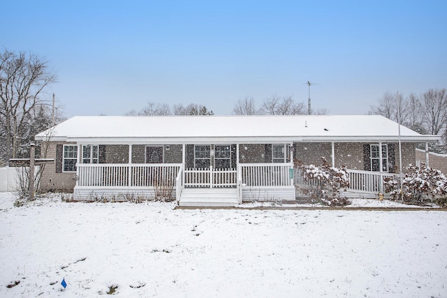 snow covered rear of property featuring covered porch