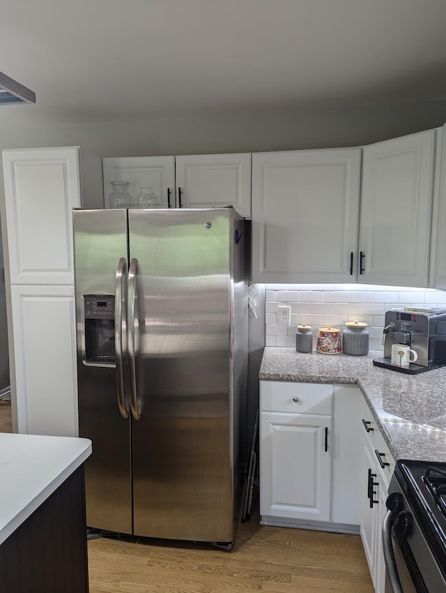 kitchen featuring light stone countertops, white cabinetry, light hardwood / wood-style flooring, and stainless steel appliances