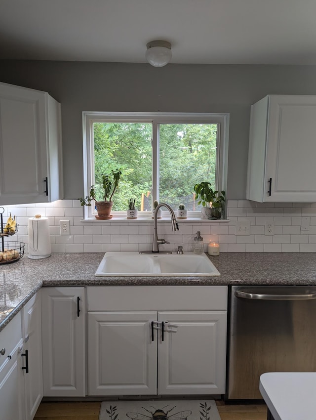 kitchen featuring stainless steel dishwasher, white cabinetry, sink, and a wealth of natural light