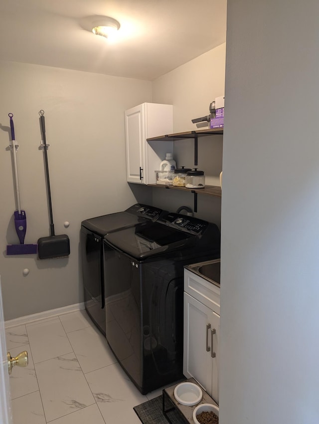 clothes washing area with cabinets and separate washer and dryer