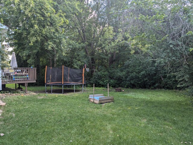 view of yard featuring a trampoline and a wooden deck