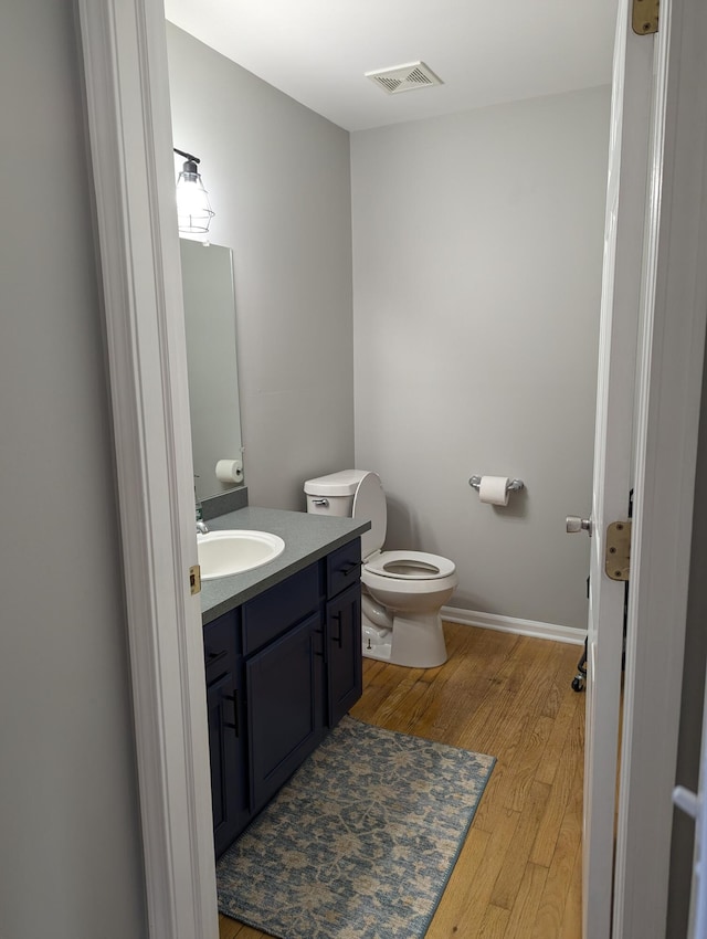 bathroom with vanity, wood-type flooring, and toilet