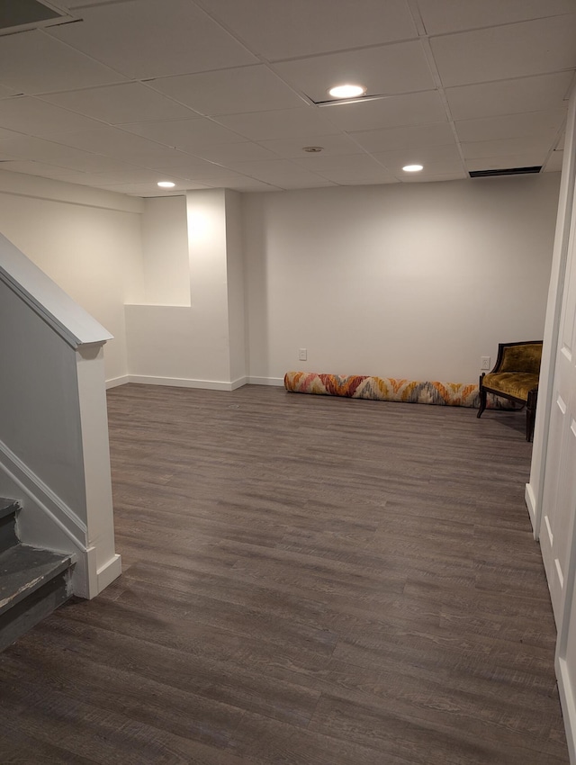 basement with dark hardwood / wood-style flooring and a paneled ceiling