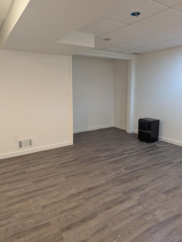 basement with a drop ceiling and dark wood-type flooring