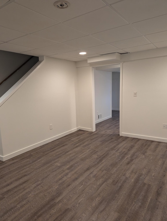 basement featuring a drop ceiling and dark wood-type flooring