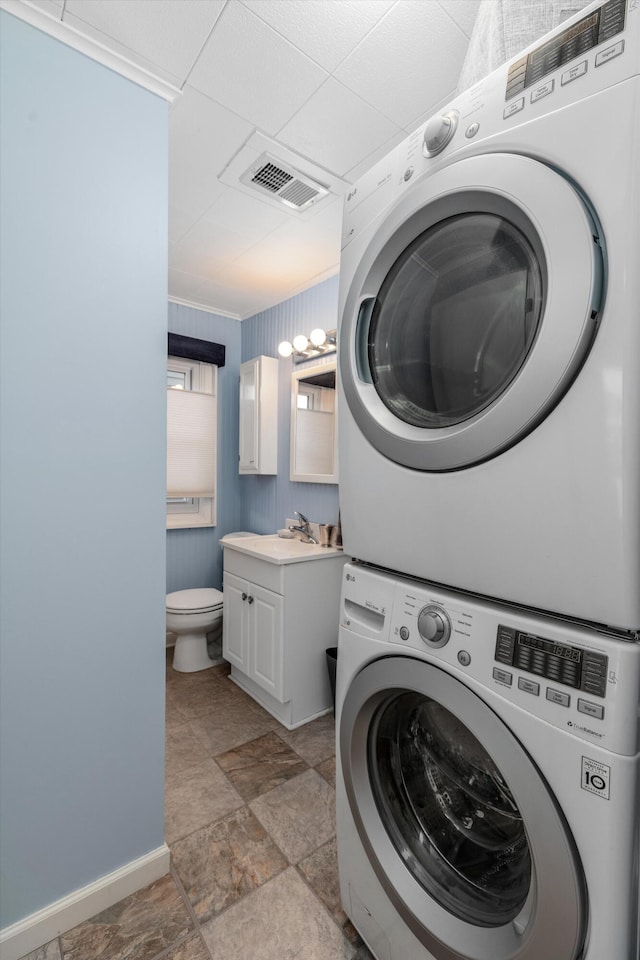 clothes washing area featuring stacked washer / dryer and sink