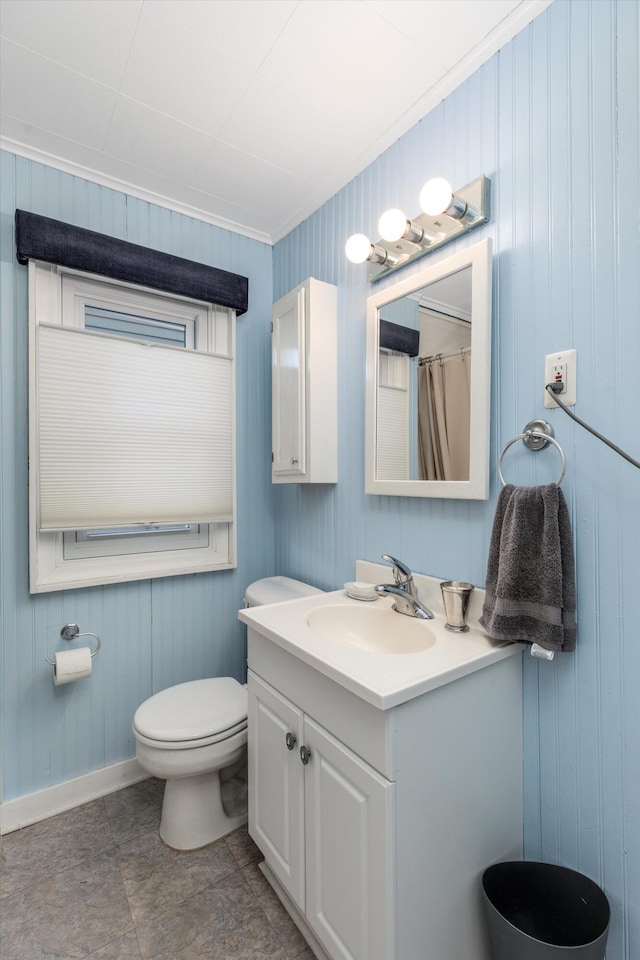 bathroom with vanity, wooden walls, crown molding, tile patterned flooring, and toilet