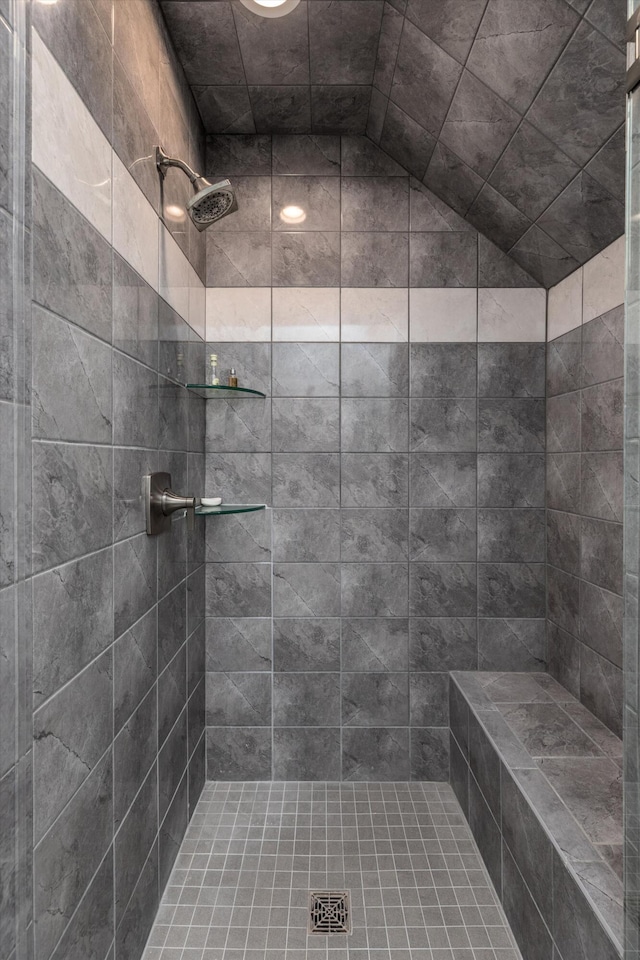 bathroom with tiled shower and lofted ceiling