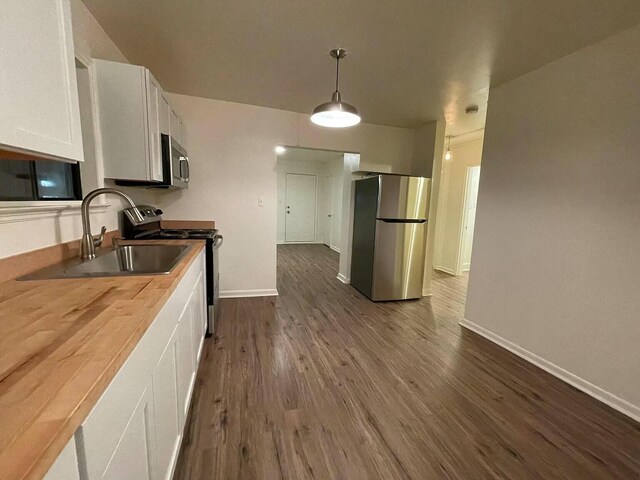 kitchen with white cabinetry, sink, stainless steel appliances, dark hardwood / wood-style floors, and decorative light fixtures