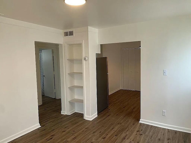 unfurnished room with built in features and dark wood-type flooring