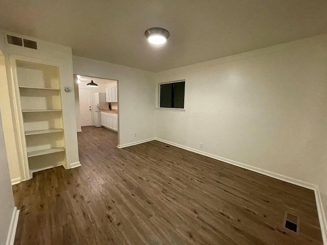 interior space with built in shelves and dark hardwood / wood-style flooring