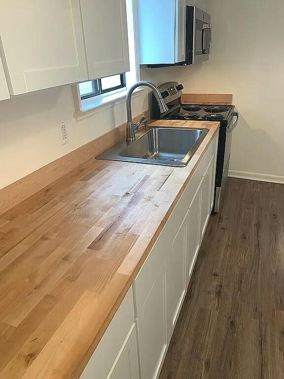 kitchen with white cabinets, appliances with stainless steel finishes, dark wood-type flooring, and sink