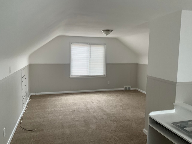 additional living space featuring carpet flooring and vaulted ceiling