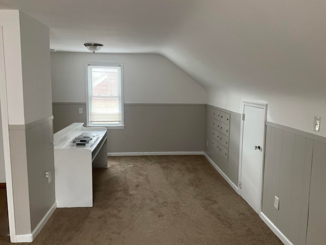 bonus room with dark colored carpet and lofted ceiling