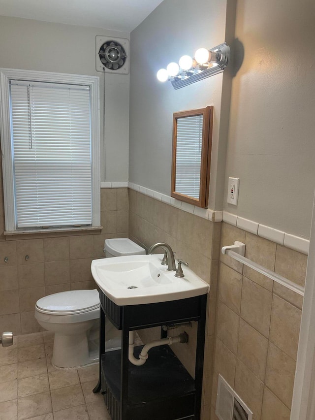 bathroom with tile patterned flooring, sink, toilet, and tile walls