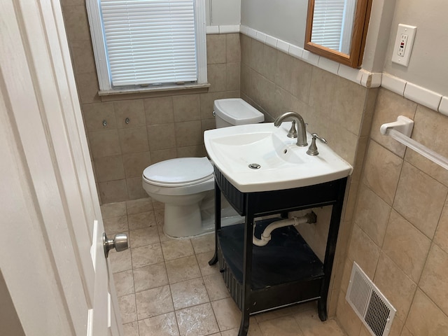 bathroom with tile patterned flooring, toilet, sink, and tile walls