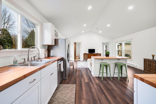 kitchen with dishwasher, dark wood-type flooring, butcher block countertops, a breakfast bar, and white cabinets