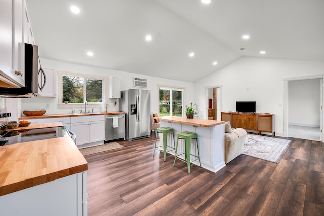 kitchen featuring wood counters, white cabinets, a kitchen bar, a kitchen island, and appliances with stainless steel finishes