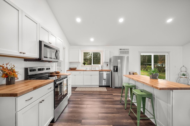 kitchen with wood counters, a kitchen breakfast bar, stainless steel appliances, white cabinets, and a kitchen island