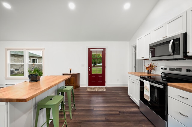 kitchen featuring wooden counters, appliances with stainless steel finishes, dark hardwood / wood-style flooring, white cabinets, and a breakfast bar area