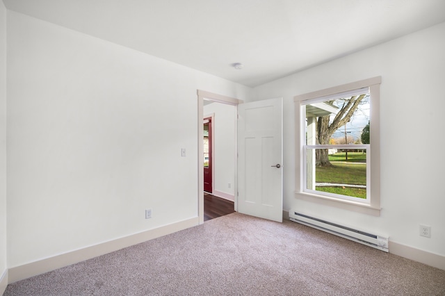 carpeted empty room with a baseboard heating unit