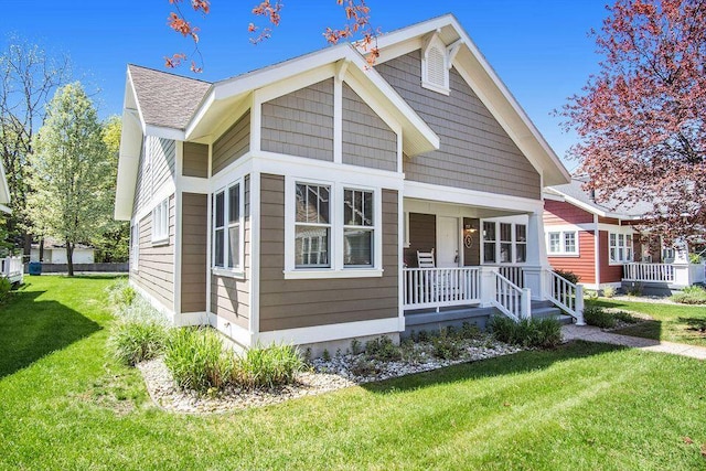 bungalow-style house featuring a porch, a front lawn, and a shingled roof