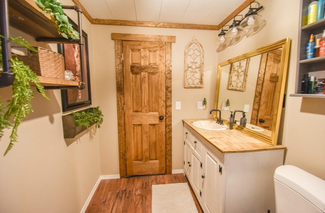 bathroom featuring hardwood / wood-style flooring, vanity, toilet, and ornamental molding