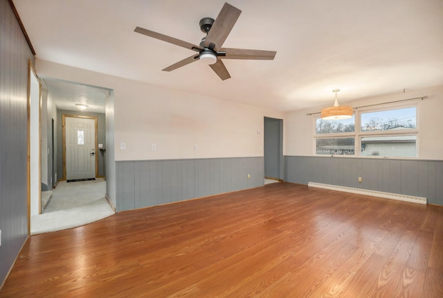 empty room featuring ceiling fan, light wood-type flooring, and baseboard heating