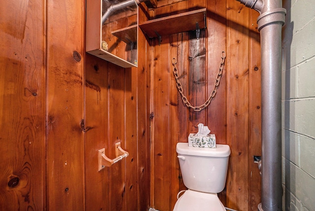 bathroom featuring wood walls and toilet