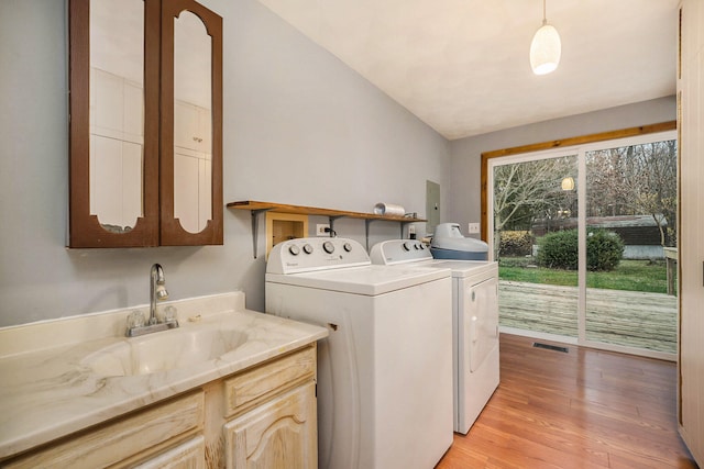 washroom featuring cabinets, light wood-type flooring, washer and clothes dryer, and sink