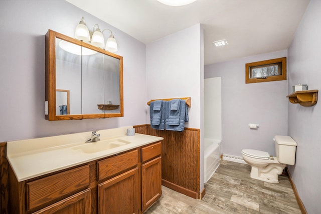 bathroom featuring a bathtub, vanity, baseboard heating, wood-type flooring, and toilet