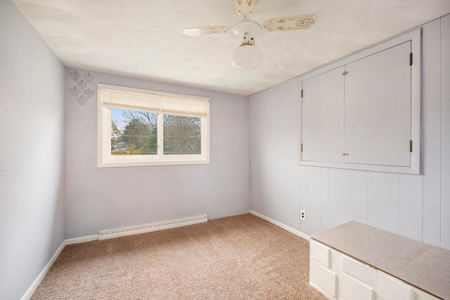 carpeted spare room with a baseboard radiator and ceiling fan